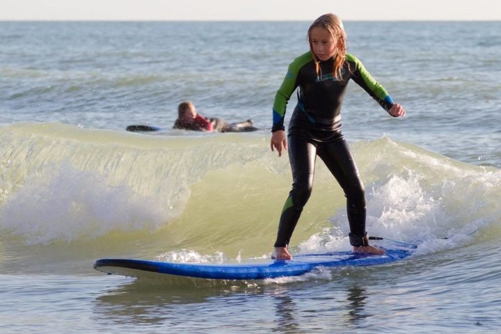 a small girl riding a wave on a surfboard in the ocean