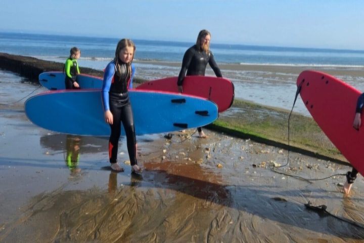 a group of people walking on a beach holding a surf board